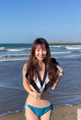 Beautiful girl takes graduation photos in the cold wind at the beach